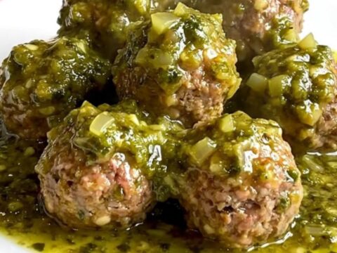 A slow cooker filled with tender turkey meatballs coated in a vibrant, chunky green salsa verde.
