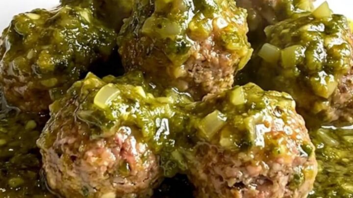 A slow cooker filled with tender turkey meatballs coated in a vibrant, chunky green salsa verde.