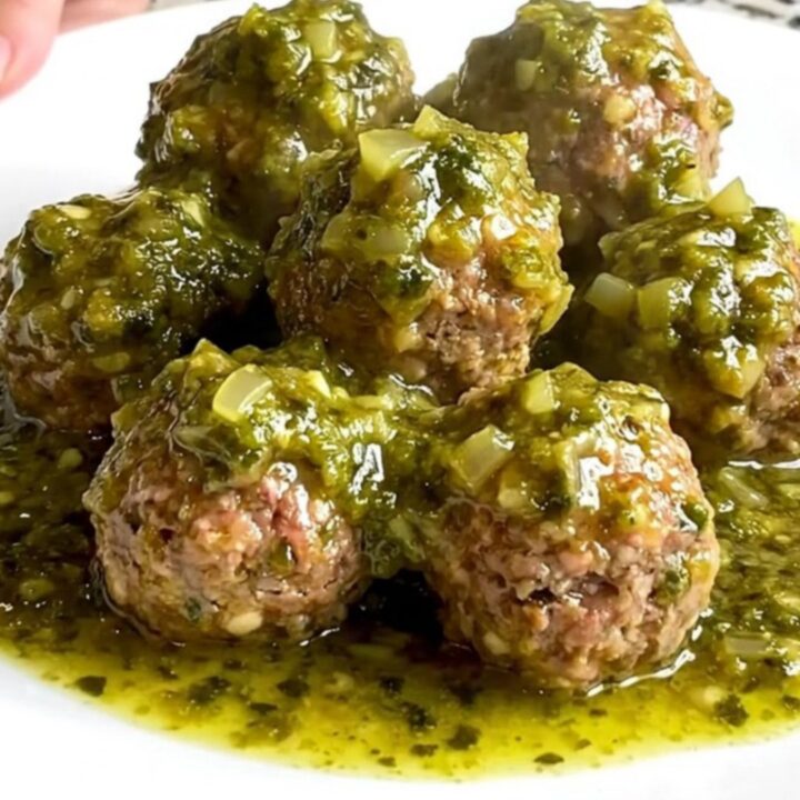 A slow cooker filled with tender turkey meatballs coated in a vibrant, chunky green salsa verde.