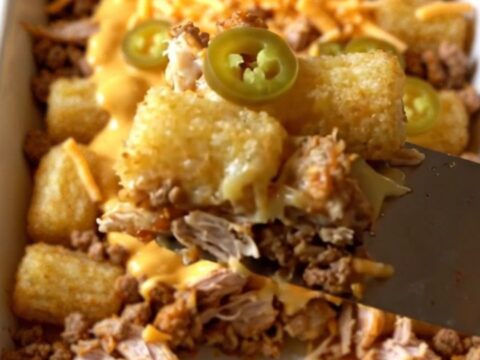 A top-down view of a rectangular ceramic baking dish filled with seasoned ground turkey and crispy potato tots.