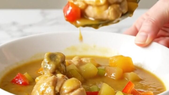 A shallow bowl of chicken etouffee with tender chicken and vegetables in a thick golden gravy.