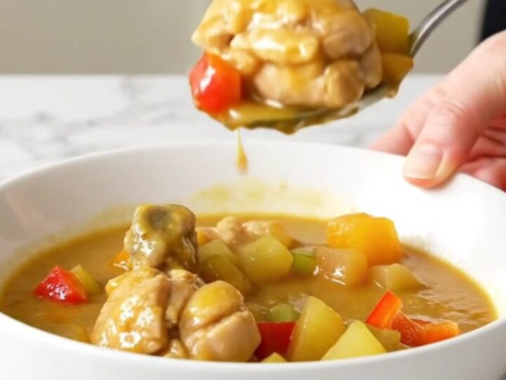 A shallow bowl of chicken etouffee with tender chicken and vegetables in a thick golden gravy.