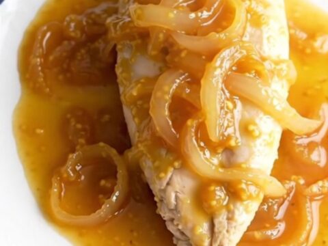 A bowl of finished apricot Dijon chicken with a thick, glossy sauce and tender onions.