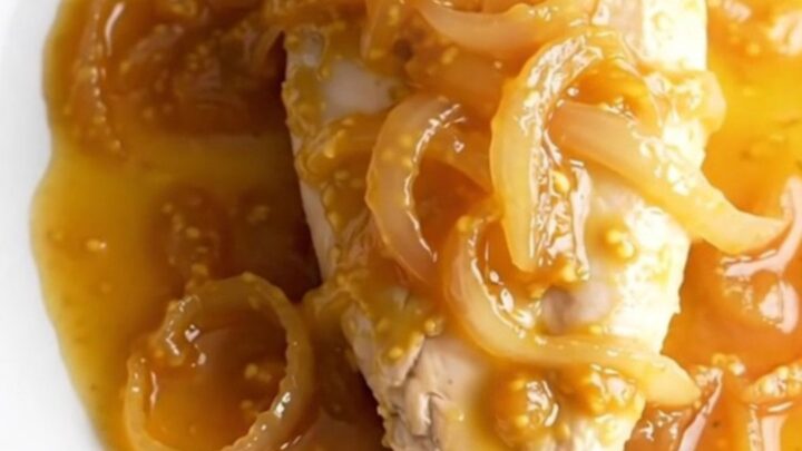 A bowl of finished apricot Dijon chicken with a thick, glossy sauce and tender onions.