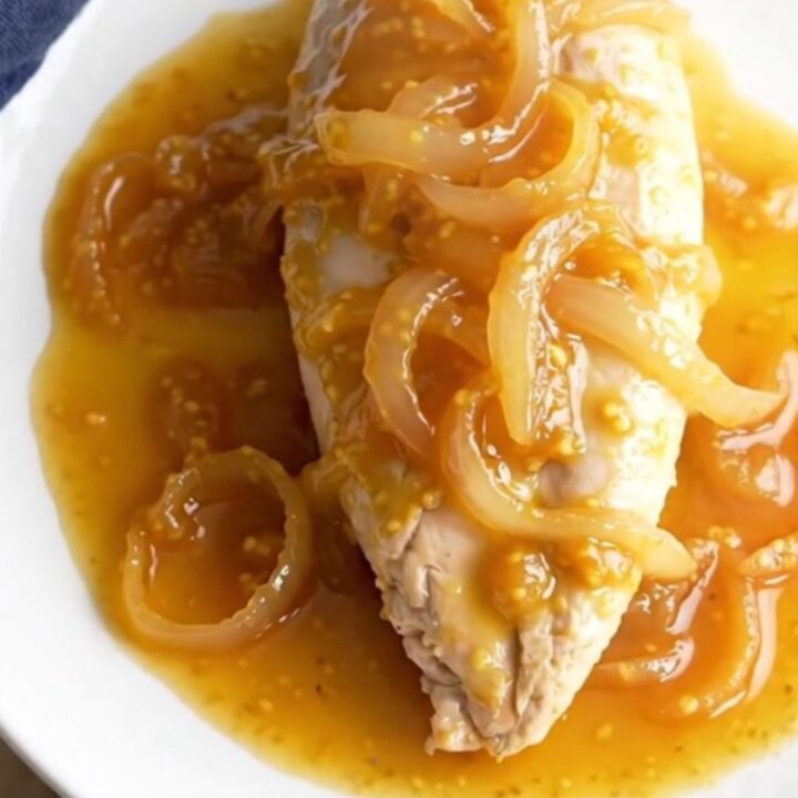 A bowl of finished apricot Dijon chicken with a thick, glossy sauce and tender onions.