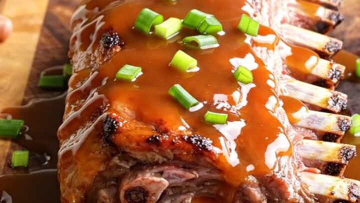 A close-up of tender, glazed honey sriracha baby back ribs arranged on a wooden serving board.