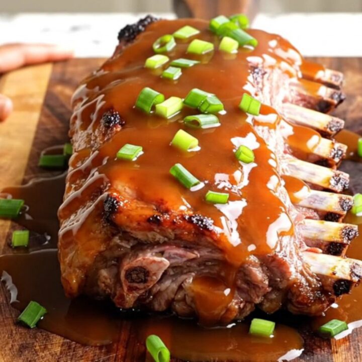 A close-up of tender, glazed honey sriracha baby back ribs arranged on a wooden serving board.
