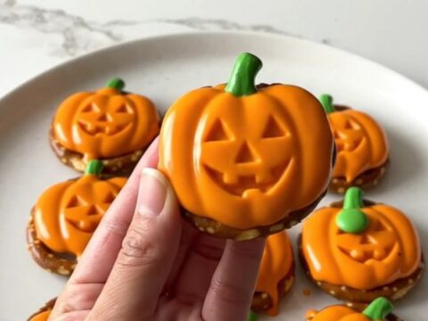 A close-up of festive pumpkin-shaped pretzel bites arranged on a white plate.