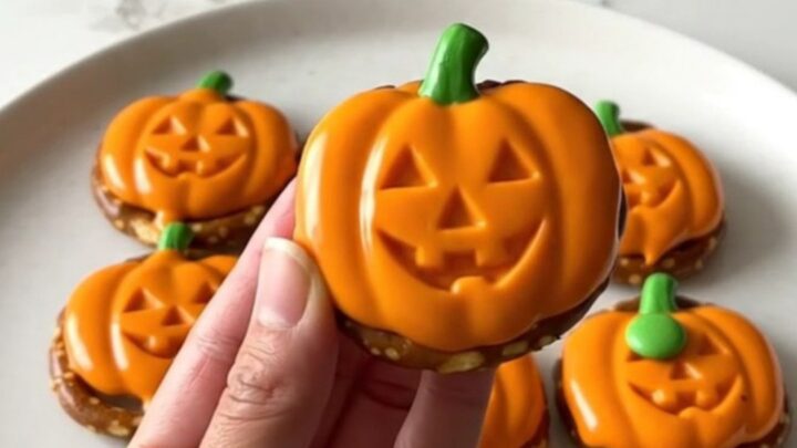 A close-up of festive pumpkin-shaped pretzel bites arranged on a white plate.