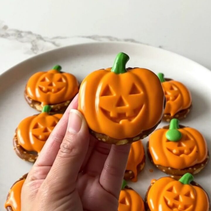 A close-up of festive pumpkin-shaped pretzel bites arranged on a white plate.