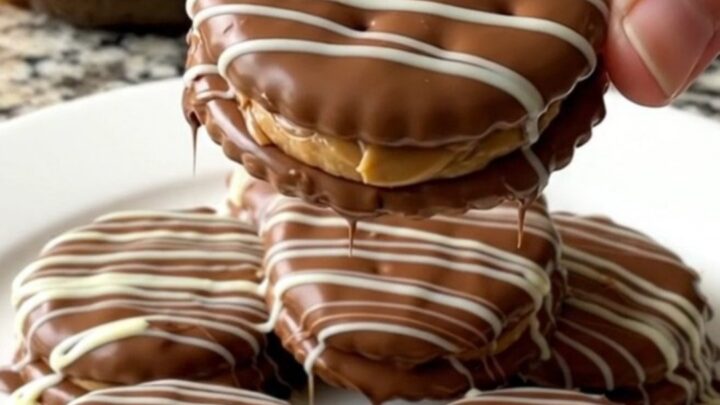 A close-up of chocolate covered peanut butter cracker sandwiches arranged neatly on a parchment-lined baking sheet.
