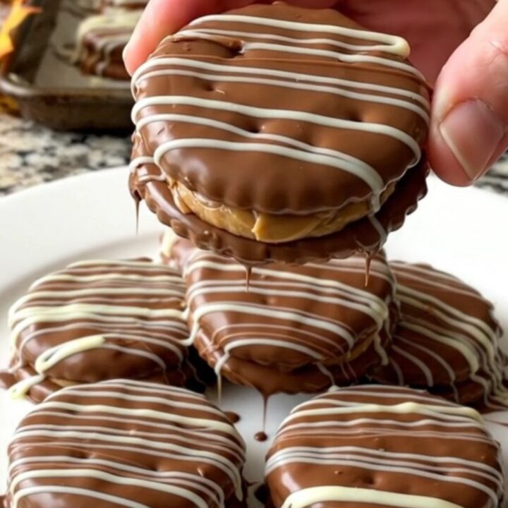 A close-up of chocolate covered peanut butter cracker sandwiches arranged neatly on a parchment-lined baking sheet.