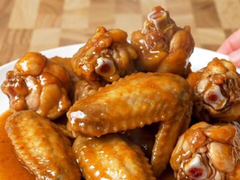 A close-up of tender, glazed chili lime chicken wings served on a white plate.