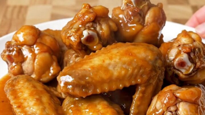 A close-up of tender, glazed chili lime chicken wings served on a white plate.