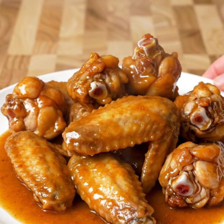 A close-up of tender, glazed chili lime chicken wings served on a white plate.