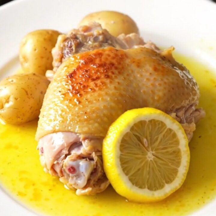 A high-angle shot of skinless bone-in turkey thighs, baby potatoes, and lemon slices in a slow cooker.