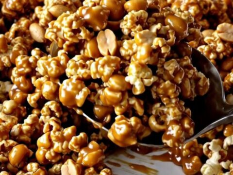 A large ceramic baking dish filled with golden caramel-coated popcorn and roasted peanuts.