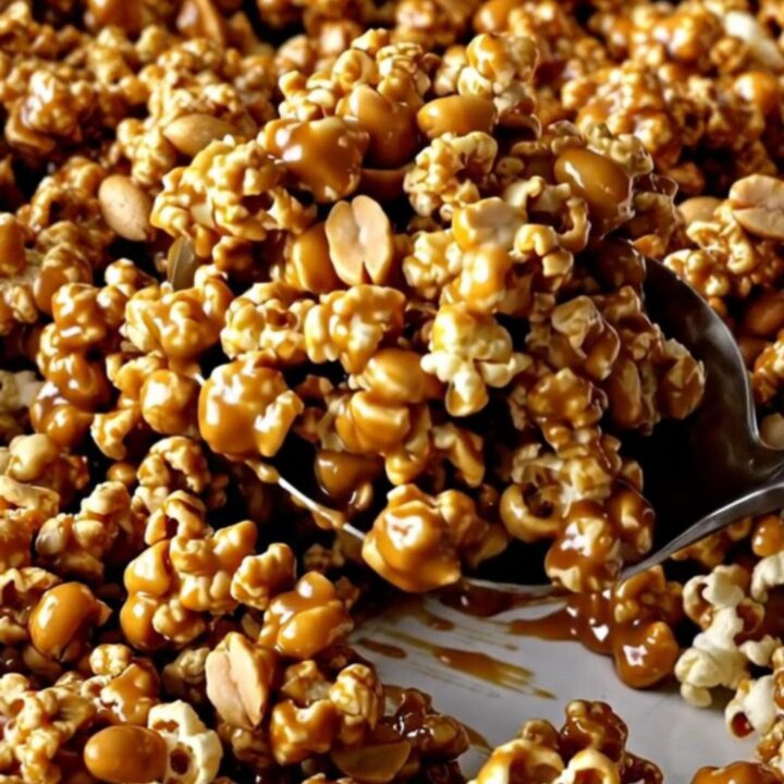 A large ceramic baking dish filled with golden caramel-coated popcorn and roasted peanuts.