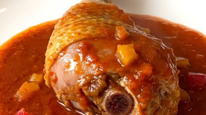 A close-up of tender, braised Creole turkey drumsticks served in a rich tomato and vegetable sauce.