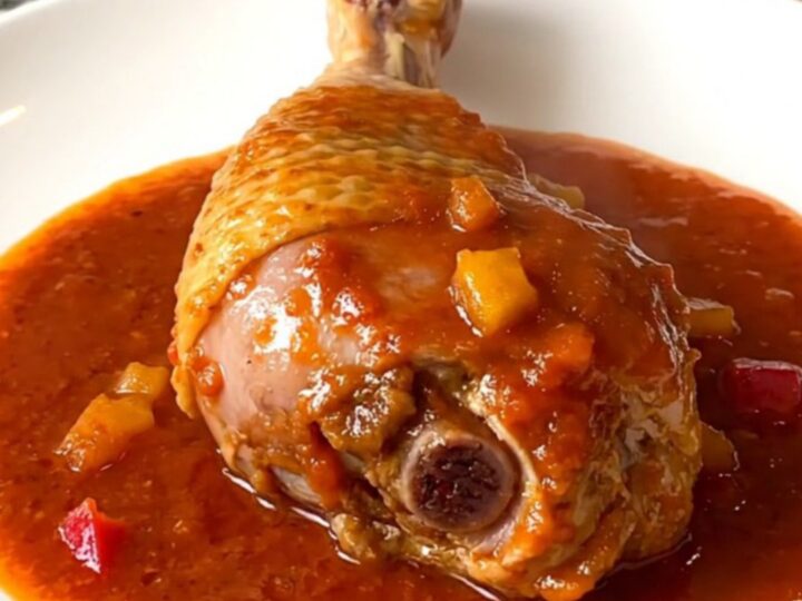 A close-up of tender, braised Creole turkey drumsticks served in a rich tomato and vegetable sauce.