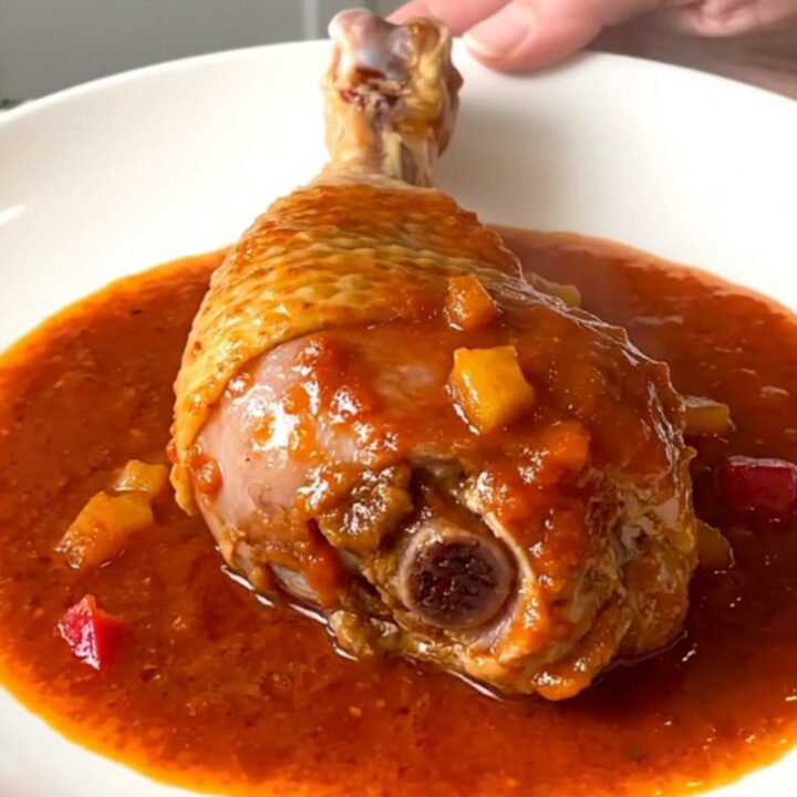 A close-up of tender, braised Creole turkey drumsticks served in a rich tomato and vegetable sauce.