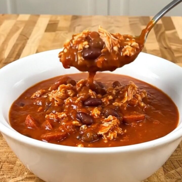 A bowl of Turkey Pizza Chili served in a white bowl with visible turkey, beans, and pepperoni.