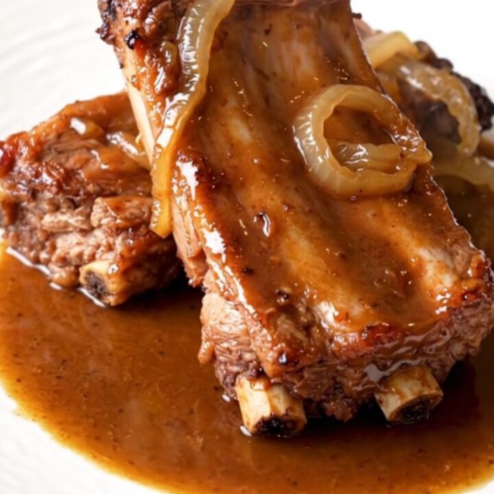 A close-up of tender, slow-cooked baby back ribs in a crockpot with a savory brown sugar and beer glaze.