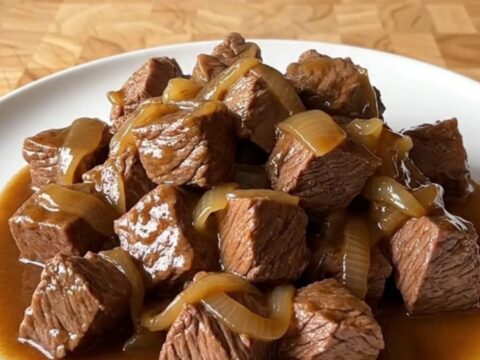 A close-up of tender beef tips in a rich brown gravy served on a white plate.
