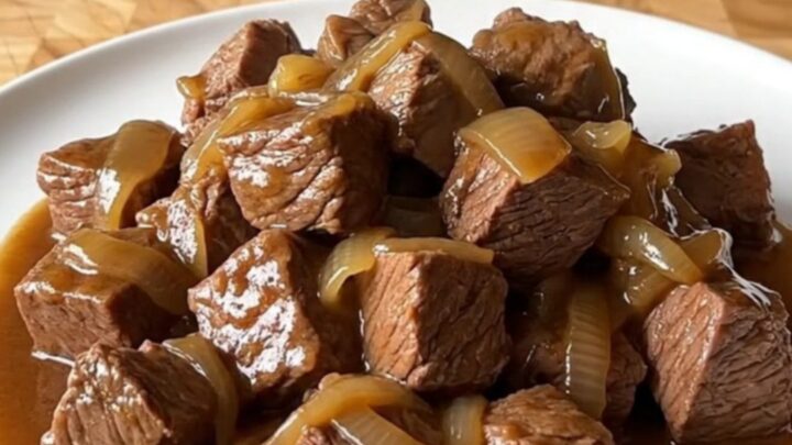 A close-up of tender beef tips in a rich brown gravy served on a white plate.