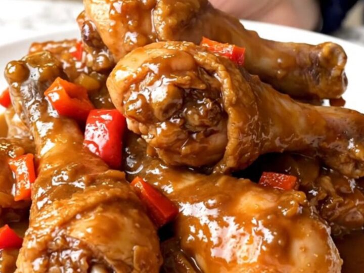 A close-up of tender jerk chicken drumsticks served on a white plate with a thick, glossy brown sugar glaze.