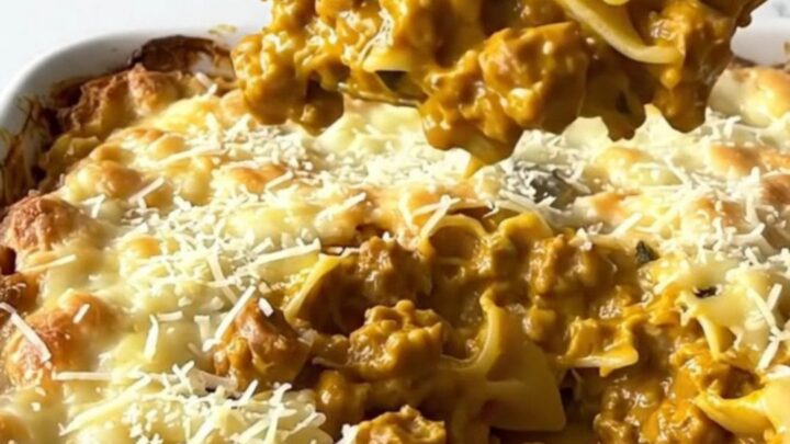 A large rectangular ceramic dish filled with creamy bowtie pasta and sausage, topped with golden parmesan.