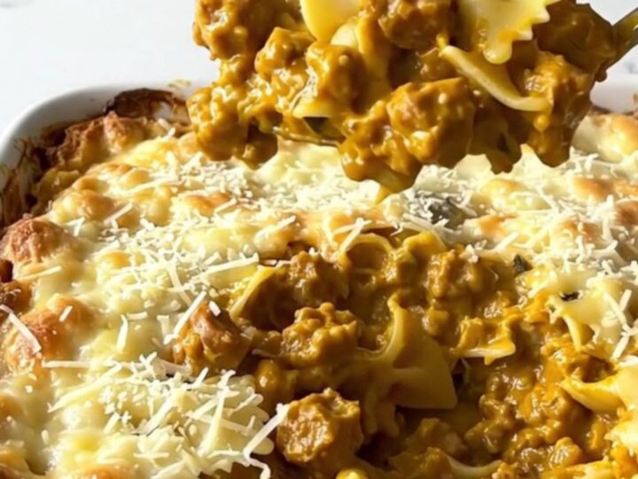 A large rectangular ceramic dish filled with creamy bowtie pasta and sausage, topped with golden parmesan.