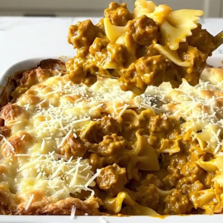 A large rectangular ceramic dish filled with creamy bowtie pasta and sausage, topped with golden parmesan.