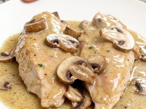 A close-up of creamy sherry mushroom chicken served on a white plate with visible steam.