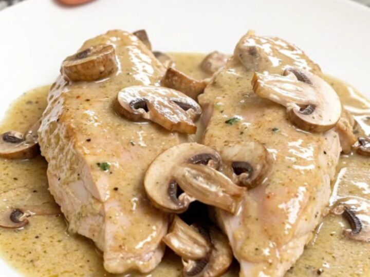 A close-up of creamy sherry mushroom chicken served on a white plate with visible steam.