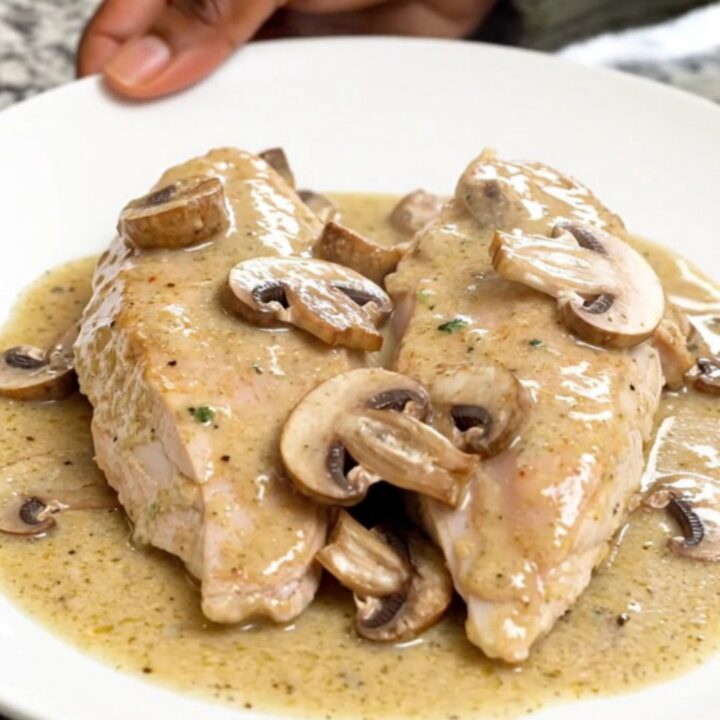 A close-up of creamy sherry mushroom chicken served on a white plate with visible steam.