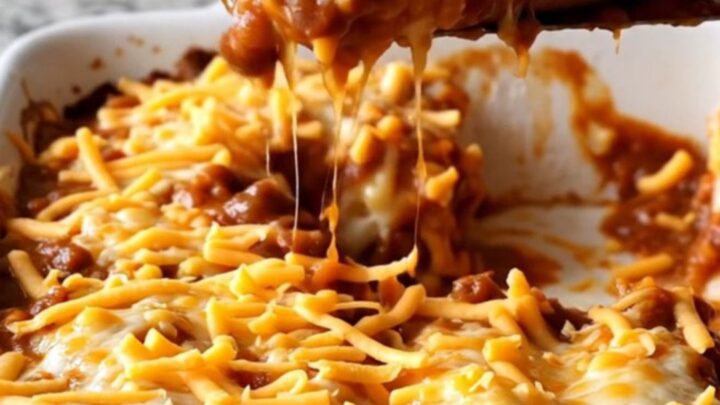 A close-up view of a chili cheese dog bake featuring melted cheddar cheese and hearty chili in a ceramic dish.