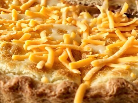 A golden-brown baked turkey cheeseburger pie in a white rectangular baking dish on a granite surface.