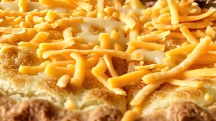 A golden-brown baked turkey cheeseburger pie in a white rectangular baking dish on a granite surface.