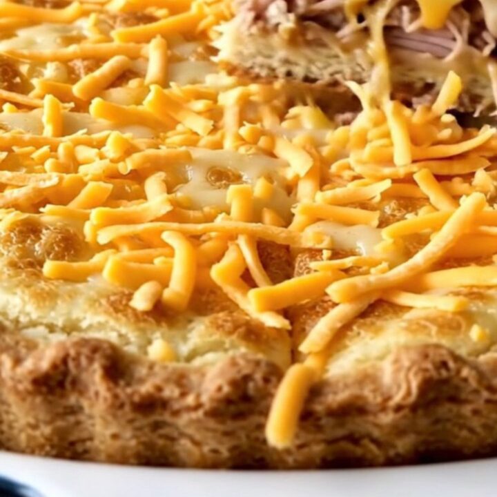 A golden-brown baked turkey cheeseburger pie in a white rectangular baking dish on a granite surface.