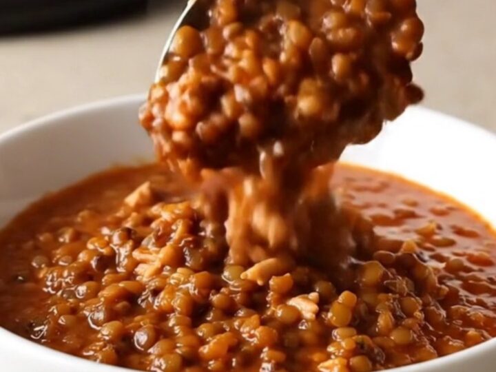 A warm bowl of slow cooker turkey and lentil chili with steam rising, set on a beige kitchen counter.