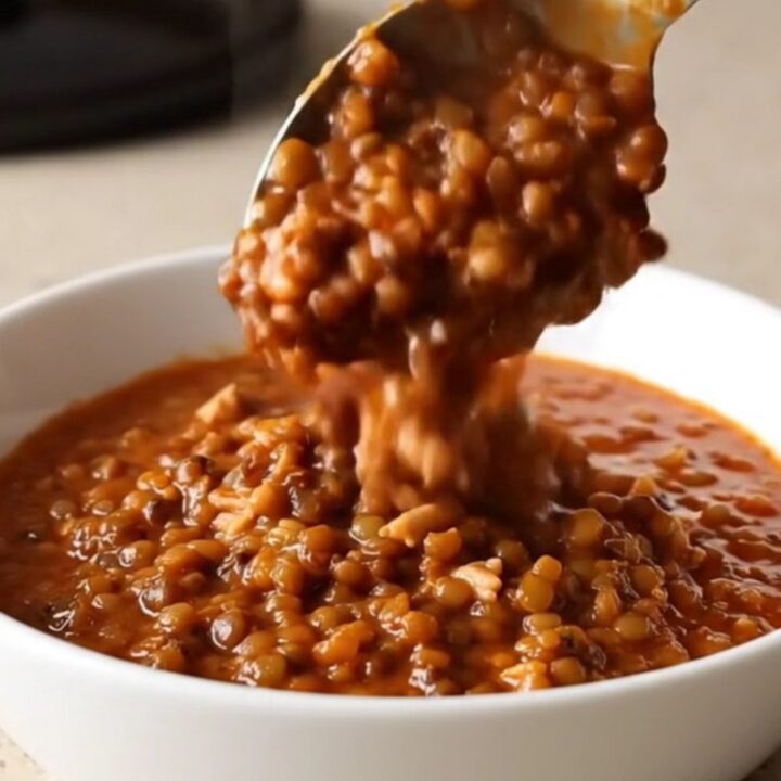 A warm bowl of slow cooker turkey and lentil chili with steam rising, set on a beige kitchen counter.