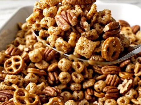 A large white rectangular dish filled with a golden, toasted pumpkin spice snack mix on a white quartz countertop.