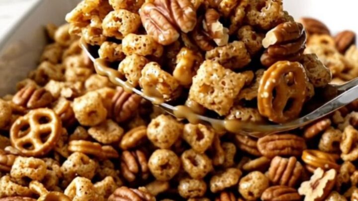 A large white rectangular dish filled with a golden, toasted pumpkin spice snack mix on a white quartz countertop.