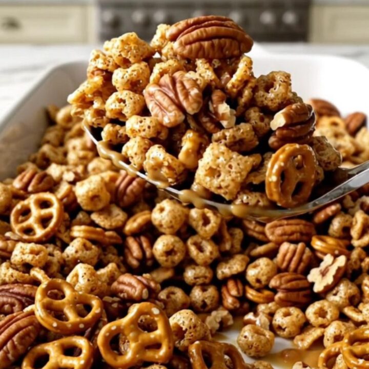A large white rectangular dish filled with a golden, toasted pumpkin spice snack mix on a white quartz countertop.