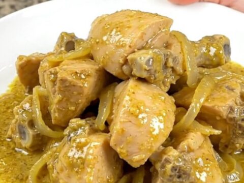 A bowl of creamy chicken korma with tender chicken chunks in a pale yellow curry sauce served over rice.