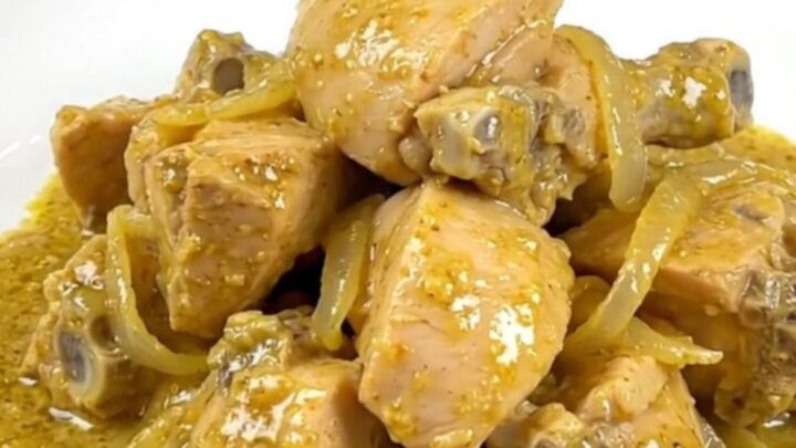 A bowl of creamy chicken korma with tender chicken chunks in a pale yellow curry sauce served over rice.