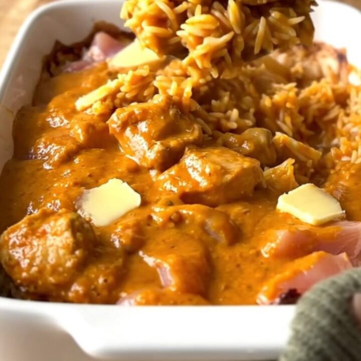 A large rectangular ceramic dish filled with creamy butter chicken and rice, fresh from the oven.