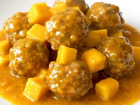 A bowl of slow-cooked turkey meatballs glazed in a thick, vibrant orange mango habanero sauce.