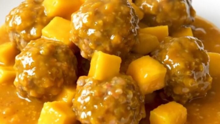 A bowl of slow-cooked turkey meatballs glazed in a thick, vibrant orange mango habanero sauce.
